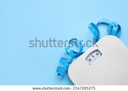 Scales and measuring tape on light blue background, flat lay. Space for text Royalty-Free Stock Photo #2167285275