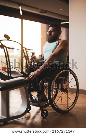 A middle-aged person in a wheelchair training in a gym.Working his back. Concept of overcoming sports.
