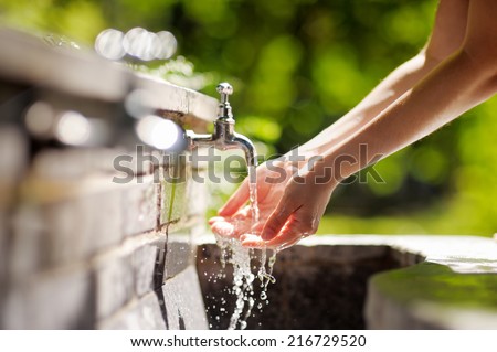 Closeup photo of woman washing hands in a city fountain 