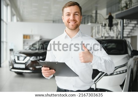 friendly vehicle salesman presenting new cars at showroom. Concept for car rental. Royalty-Free Stock Photo #2167303635