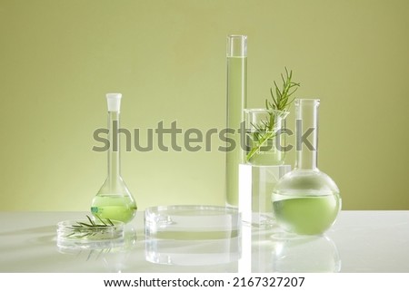 Photoshoot over the course of experiment on green leaf , the research on chemistry lab , fluid in beaker and laboratory equipment and transparent podium with blank space for product Royalty-Free Stock Photo #2167327207