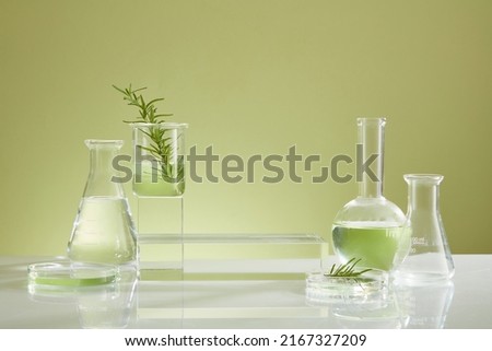 Photoshoot over the course of experiment on green leaf , the research on chemistry lab , fluid in beaker and laboratory equipment and transparent podium with blank space for product Royalty-Free Stock Photo #2167327209