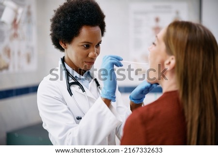 African American doctor examining woman throat during medical appointment at doctor's office. Royalty-Free Stock Photo #2167332633