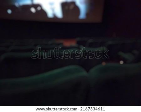 abstract dark blur image, green seat inside movie theater or Cinema, with big screen display.
