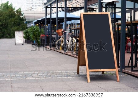 Blank wooden sandwich board near outdoor cafe. Mockup for design