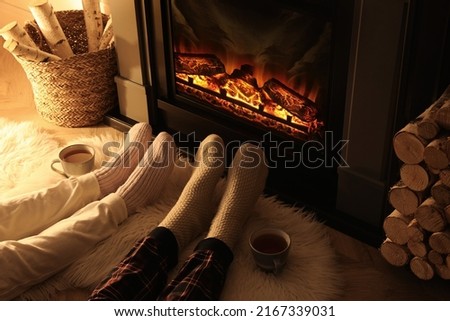 Couple in knitted socks near fireplace at home, closeup of legs Royalty-Free Stock Photo #2167339031