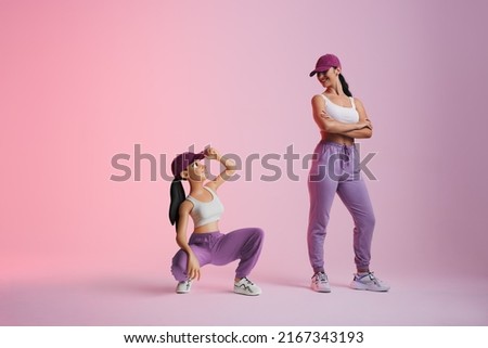 Happy young woman smiling at her metaverse avatar in a studio. Cheerful young woman standing next to the 3D simulation of herself. Sporty young woman exploring virtual reality. Royalty-Free Stock Photo #2167343193