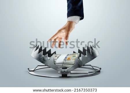 A man's hand takes dollars from a bear trap. The concept of mortgage, dirty money, bribe, corruption, easy money, debt, credit. mixed media Royalty-Free Stock Photo #2167350373