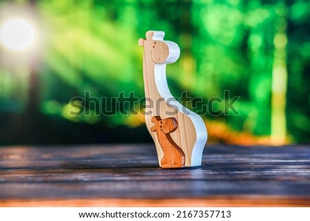 Wooden puzzle in the form of a family of handmade giraffes on the background of the forest