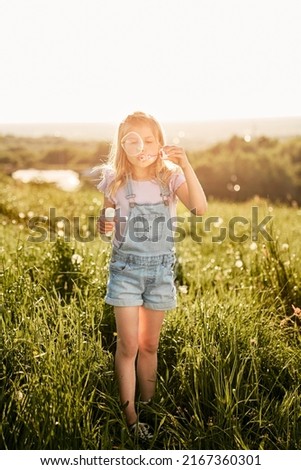 Caucasian girl playing with bubbles on the meadow  