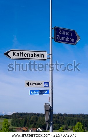 Direction signs with street lights and scenic rural landscape at village Forch, Canton Zürich, on a sunny summer day. Photo taken June 8th, 2022, Forch, Switzerland.