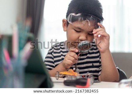 Young asia student remotely learn online at home  in coding robot car and electronic board cable in STEM, STEAM, mathematics engineer science technology computer code in robotics for kids. Royalty-Free Stock Photo #2167382455