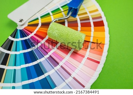 Repair brushes and color palette on a green background. The concept of apartment renovation. The choice of color for the repair and painting of the walls.