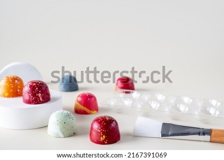 Colorful homemade chocolate bonbons. Modern hand painted chocolate candy. Chocolate pralines, mold and brush for painting  Royalty-Free Stock Photo #2167391069