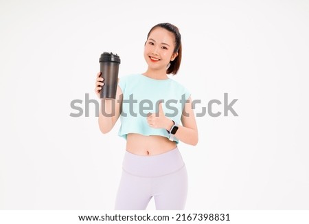 Portrait of Asian young beautiful and cheerful sporty woman with shake bottle in hand, isolated on background