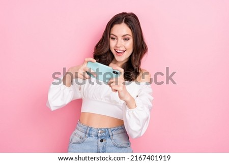 Photo of happy excited cheerful young girl spend free time playing phone videogames isolated on pink color background