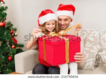family, christmas, x-mas, happiness and people concept - smiling father and daughter in santa helper hats opening gift box