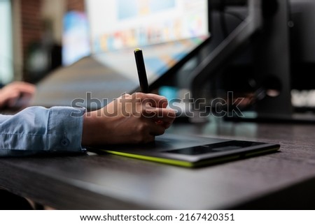 Closeup of creative graphic designer using stylus pen and graphic tablet to edit photos. Digital photo editor sitting at desk with multiple displays while using editing software to retouch images.