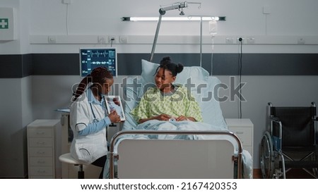 Medic holding tablet with cardiology figure to show diagnosis to woman in bed. Medical physician explaining cardiovascular exam results on device screen to sick patient. Healthcare checkup Royalty-Free Stock Photo #2167420353