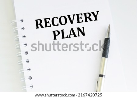 Text RECOVERY PLAN on a notepad on a table next to a pen, a business concept