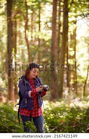 Woman On Hike Through Forest Taking Photo On DSLR Camera