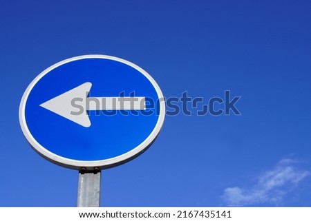 round traffic sign with arrow over blue sky