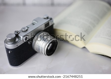 Vintage camera next to an open book on a light background