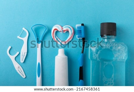 Toothbrush, tongue cleaner, floss, toothpaste tube and mouthwash on blue background with copy space. Flat lay. Dental hygiene. Oral care kit. Dentist concept. Royalty-Free Stock Photo #2167458361