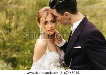 Stylish beautiful newlywed couple in love kissing together in nature.