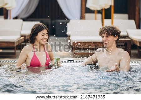 The guy flirts with a girl in the hot tube. Couple relaxing in the pool and enjoying the summer.