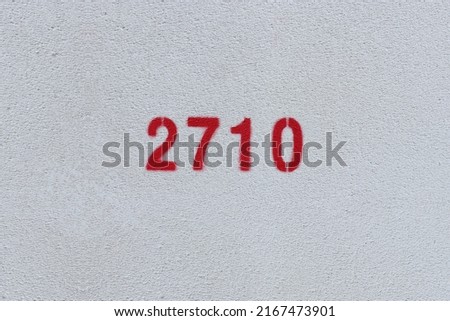Red Number 2710 on the white wall. Spray paint.
