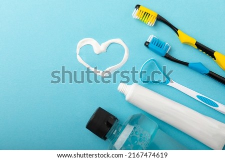 Heart symbol made from toothpaste. A tube of toothpaste and a toothbrush on a blue background. Refreshing and whitening toothpaste. Copy space for text. flat lay