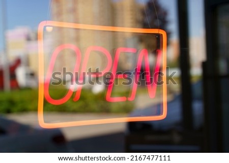 Neon sign open on the glass door of a shop or cafe. Selected focus
