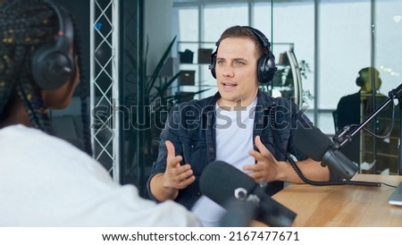 A Male Presenter Communicates with a Guest, an African American, During a Radio Broadcast at a Table in a Recording Studio, Broadcasts a Live Radio Interview With Spbd. Royalty-Free Stock Photo #2167477671