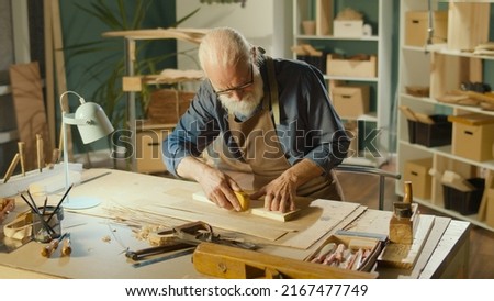Professional Elderly Man Carpenter Working on Wood Using Carpentry Tools in the Garage. Craft Authentic Workshop. Handicraft, Creative Small Business. Profession, Art and Hobby Concept.