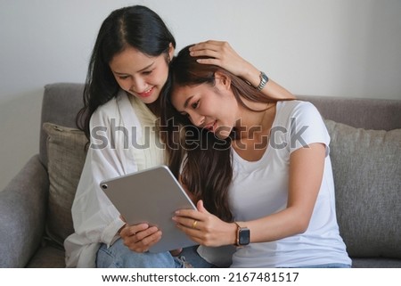 lgbtq, lgbt concept, homosexuality, two beautiful women in love happily playing tablet in a cozy home