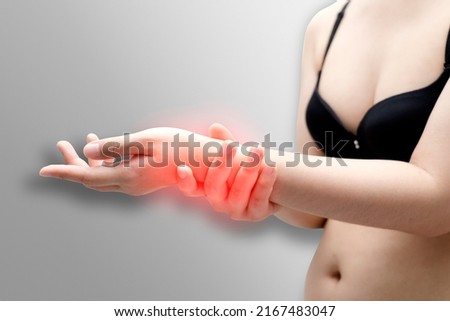 Closeup of woman arms holding her painful wrist caused by prolonged work on the computer, laptop. Carpal tunnel syndrome, arthritis, neurological disease concept. Numbness of the hand