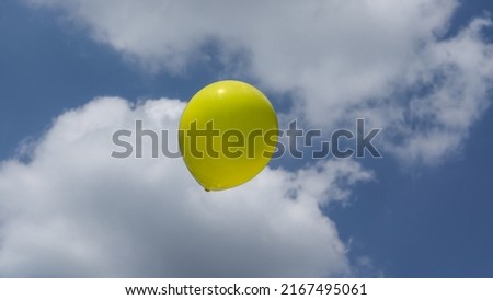 a yellow balloon flies in the sky as a symbol of freedom
