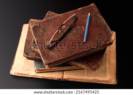 Stack of old worn jewish books in leather binding on open Torah pages on dark background. Closeup. Selective focus Royalty-Free Stock Photo #2167495425