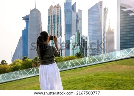 Female tourist making photos of the skyline of Doha, Qatar, during sunset time in the park