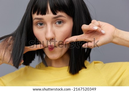 a funny, playful, emotional woman makes a funny face by pursing her lips and holding her fingers on her cheeks. Horizontal photo 