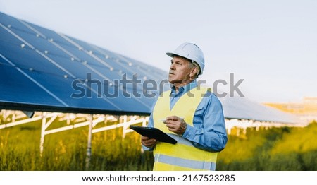 Portrait of engineer working with digital tablet at solar farm. Alternative Eco energy concept