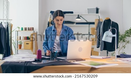 Successful Businesswoman Tailor Girl Works with Sketches of Clothes Using a Laptop. Creation of an Individual Costume in a Luxurious Atelier. Handicraft, Sewing Small Business, Fashion Industry.