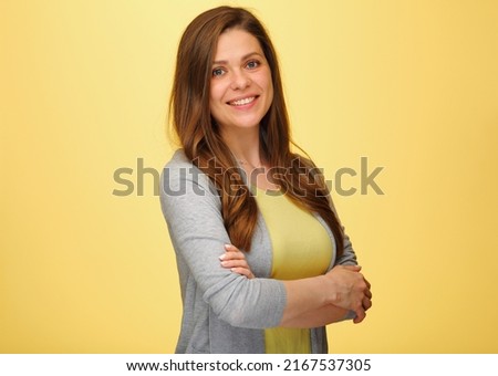 Smiling woman standing with crossed arms. isolated female portrait on yellow background.