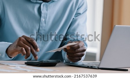 Close up unknown african man banker accountant hold payment incomes outcomes utility bills make calculation of unpaid bank debt make audit check credit balance manage monthly budget reconcile accounts Royalty-Free Stock Photo #2167537639