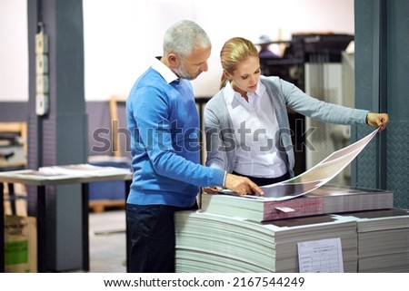 Making sure every little nuance is perfect. Two publishers assessing the quality of printed work in a factory. Royalty-Free Stock Photo #2167544249