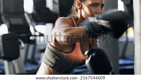 Dont pull your punches. Cropped shot of a young female boxer working out on a punching bag in the gym. Royalty-Free Stock Photo #2167544609