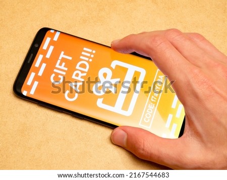 Man redeeming a generic gift card voucher on his smartphone, receiving a coupon code in app, mobile phone, hand closeup. Online advertising, internet marketing campaign simple concept, one person