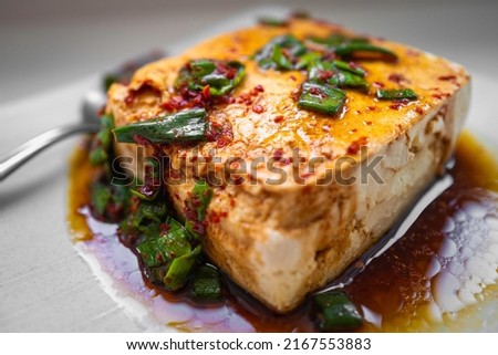 Tofu with Korean spicy soy and sesame oil sauce and chopped scallion, close-up