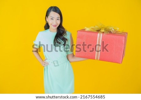 Portrait beautiful young asian woman smile with red gift box on color background
